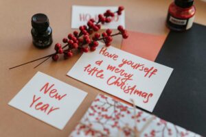 A handwritten paper that says Have yourself a merry little christmas, one that says new year, and one that says ho ho ho surrounded by red indicating winter and Christmas time